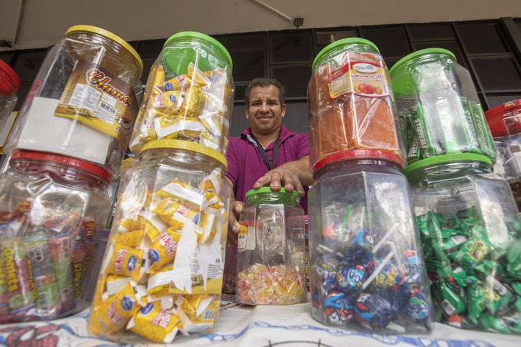 Brasília (DF) 21/04/2023 - Especial 63 anos de Brasília, os candangos da cidade. Fábio de Araújo posa para fotografia em sua mesa com doces no setor comercial.
Foto: Joédson Alves/ Agência Brasil
